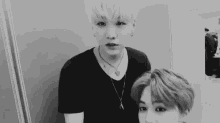 a black and white photo of two young men standing next to each other in a room .