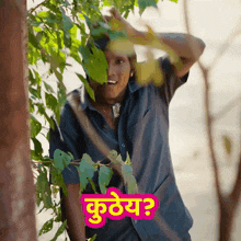a man peeking out from behind a tree with a pink sticker that says kutey