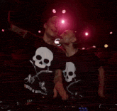 a man wearing a skull t-shirt is covering his mouth with his hand