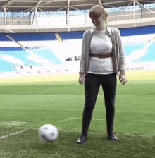 a woman is kicking a soccer ball in a stadium