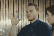 a man in a blue shirt and tie is holding a red ball in his hand
