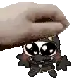 a hand is holding a cartoon character with big eyes and a hat .