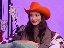 a woman wearing a red cowboy hat sitting in front of a microphone