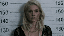 a woman is standing in front of a police lineup with the number 130 on it