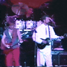a man playing a guitar and a man playing drums on stage