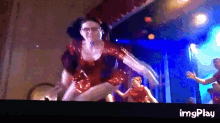 a woman in a red dress is dancing on a stage in front of a screen that says img play
