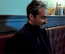 a man with a beard is sitting in a restaurant .