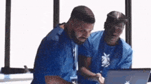 two men are looking at a laptop computer together .