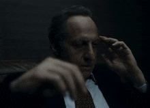 a man in a suit and tie is holding his head