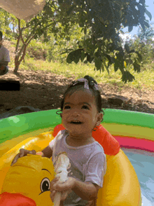 a little girl is sitting in an inflatable duck float