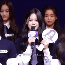 a girl is holding a microphone in front of a group of girls and says jeemin de azul