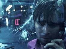 a man is talking on a cell phone in front of a broken glass