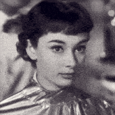 a close up of a woman 's face with a silver cloth around her neck