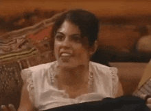 a woman is sitting on a couch making a funny face and looking at the camera .