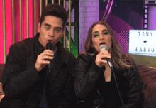 a man and a woman singing into microphones with a sign that says dany and fabio in the background