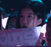 a woman is holding a sign that says ' oii ' on it