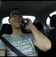 a man wearing a shirt that says classic garage on it is talking on a cell phone