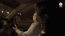 a woman is driving a car with chinese writing on the steering wheel
