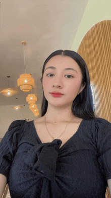 a woman in a black top is taking a selfie in front of a wooden wall