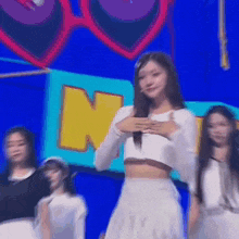 a woman in a white crop top and white skirt is standing on a stage .