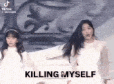 two girls are dancing on a stage with the words `` killing myself '' written on the bottom .