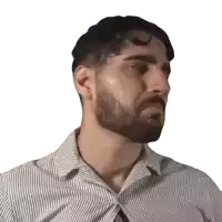 a man with a beard wearing a striped shirt looks to his left