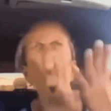 a blurry picture of a man 's face with his hands in front of his face