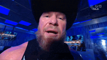 a man with a beard wearing a cowboy hat and a black tank top with the word smack on it