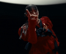 a woman in a red and black dress is making a gesture with her finger