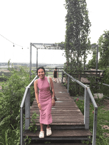 a woman in a pink dress is standing on a wooden walkway with a sign above her that says " cane peak "