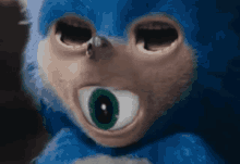 a close up of a blue stuffed animal with green eyes