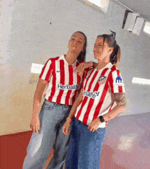 two women wearing red and white striped shirts with herbalife written on the front