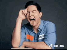 a man wearing a blue shirt with the word msgm on it is sticking out his tongue .