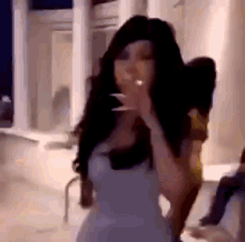 a woman in a white dress is standing in front of a building and blowing a kiss .