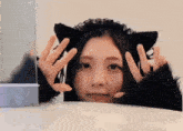 a woman wearing a cat ear headband is making a funny face .