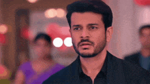 a man with a beard is making a surprised face while standing in front of a blurry background .