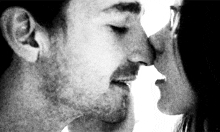 a black and white photo of a man and a woman kissing