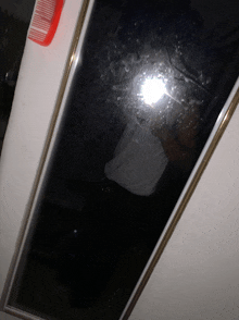 a mirror with a red comb hanging on it