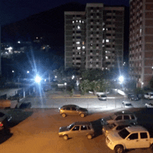 several cars are parked in a parking lot at night