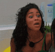 a woman with a surprised look on her face is wearing a green top