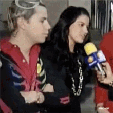 a man and a woman are standing next to each other and talking into microphones .