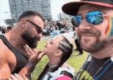 a man with a beard is touching a woman 's face while another man looks on .