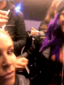 a group of people are sitting in a room and one of them has purple hair .