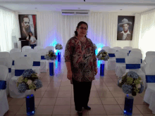 a woman stands in front of a row of white chairs with blue ribbons