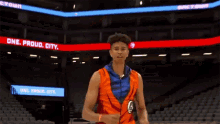 a man in a basketball uniform stands in front of a sign that says proud city