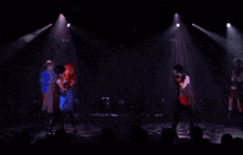 a group of people are dancing on a stage with a crowd watching