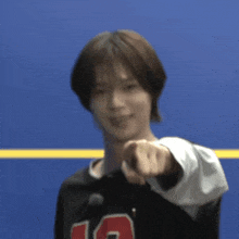 a young man wearing a black shirt with the number 10 on it pointing at the camera .