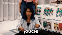 a woman with blue hair says ouch in front of a blanket with elephants on it