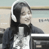 a woman wearing headphones is smiling in front of a microphone with the hashtag tiktok visible