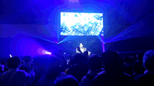 a crowd of people at a concert with a large screen behind them that says ' ec ' on it